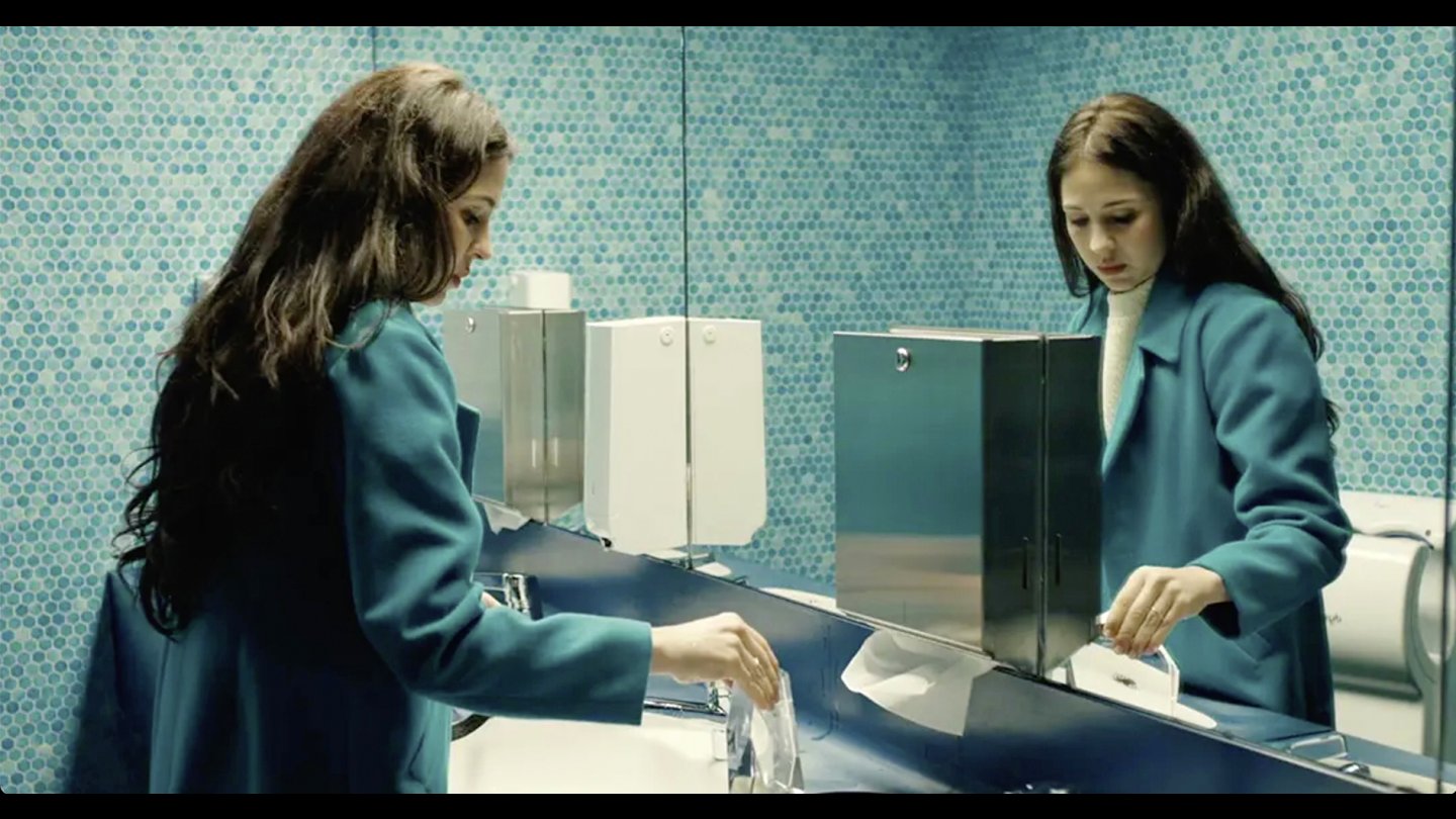 Filmstill aus LAS CORRIENTES: Eine Frau steht vor einem Spiegel in einem Badezimmer.