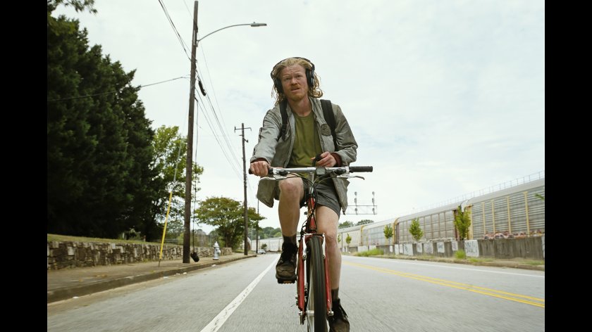 Filmstill aus BUGONIA. Ein Mann sitzt auf einem Fahrrad und fährt Richtung Kamera.