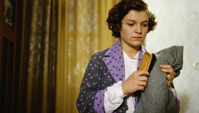 Filmstill aus ZECHMEISTER: Eine Frau hat einen Mantel in der Hand.
