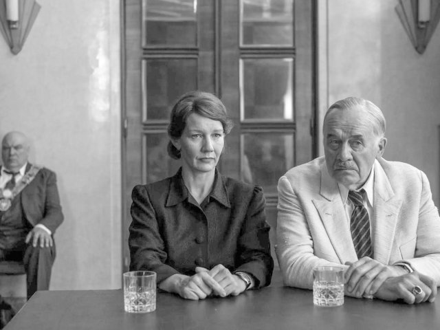 Ein schwarz-weiß Bild, eine Frau und ein Mann sitzen an einem Tisch. Sie wirken ernst.