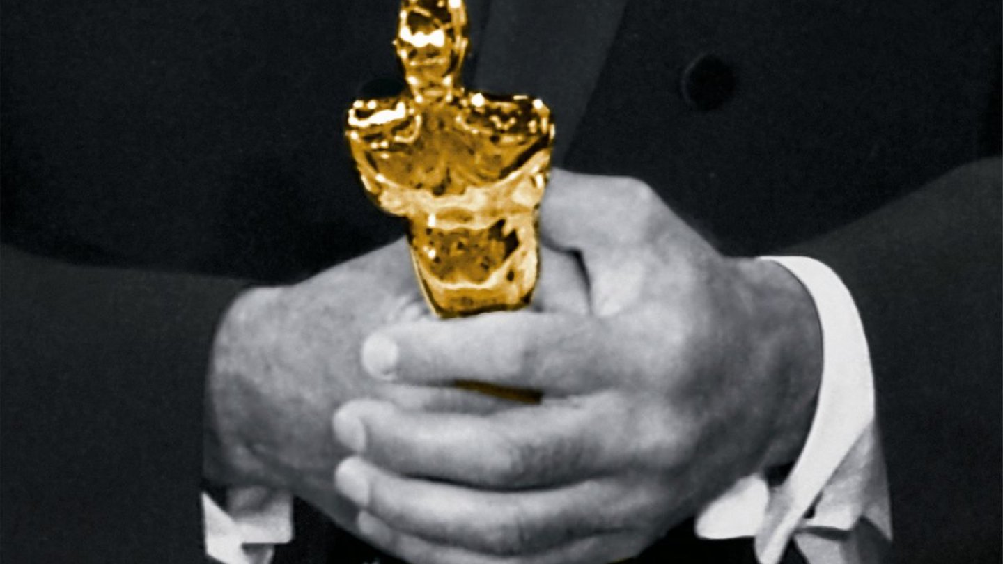 Schwarz-Weiße Männerhände halten einen goldenen Oscar, 2024