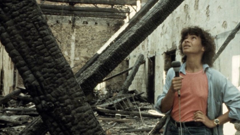 FIlmstill Jocelyne Saab: Frau mit Mikrofon steht in einem ausgebrannten, zerstörten Gebäude und blickt nach oben