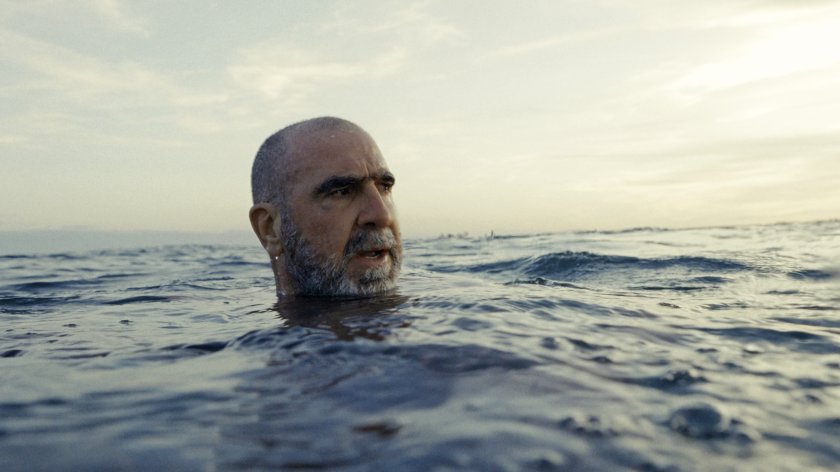 Ein Mann befindet sich in einem Gewässer, wahrscheinlich ein Meer, zu sehen ist nur sein Kopf. Er wirkt verwirrt, das Wasser unruhig.