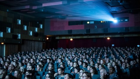 Der volle Saal des Gartenbaukinos während eines Screenings. Über den Köpfen des Publikums strahlt der Projektor in Richtung Leinwand.