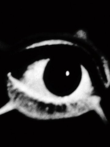 Schwarz-weiße Nahaufnahme eines stilisierten Auges mit verlängerten Wimpern auf dunklem Hintergrund